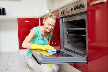 Image showing happy woman cleaning cooker at home kitchen