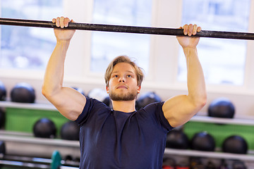 Image showing man exercising on bar and doing pull-ups in gym