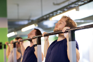 Image showing group of young men doing pull-ups in gym