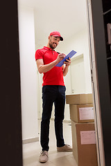 Image showing delivery man with boxes and clipboard at door