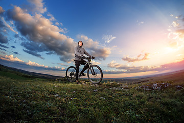 Image showing Young man cycling on a rural road through meadow