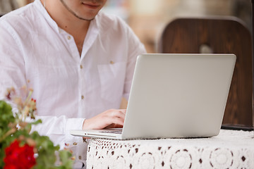 Image showing Man working on laptop at the wooden table outdoors