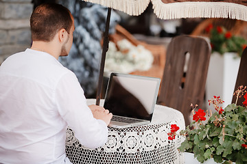 Image showing Man working on laptop at the wooden table outdoors