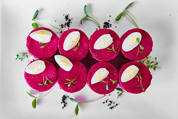 Image showing layered salad with herring, beets, carrots, onions, potatoes and eggs close-up on a plate. horizontal.