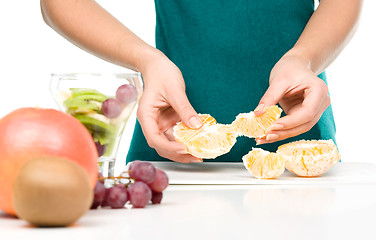 Image showing Cook is tearing orange for fruit dessert