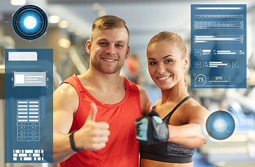 Image showing smiling man and woman showing thumbs up in gym