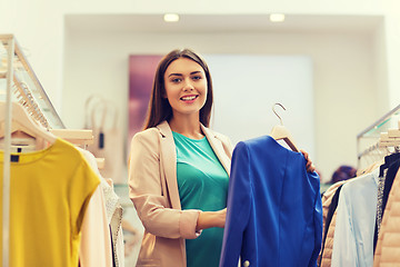 Image showing happy young woman choosing clothes in mall