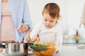 Image showing baby with vegetables and mother cooking at home