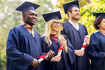 Image showing happy students in mortar boards with diplomas