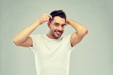 Image showing happy man brushing hair with comb over gray