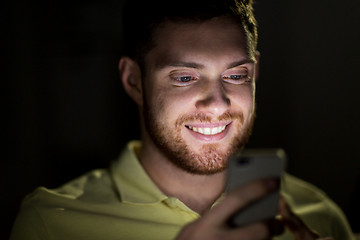 Image showing happy young man with smartphone at night