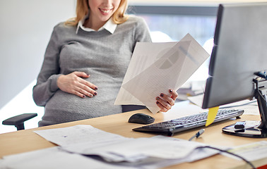 Image showing pregnant businesswoman reading papers at office