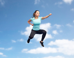 Image showing happy sporty young woman jumping in fighting pose