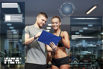 Image showing smiling young woman with personal trainer in gym