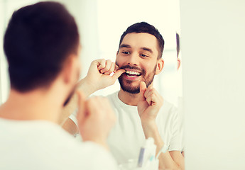 Image showing man with dental floss cleaning teeth at bathroom