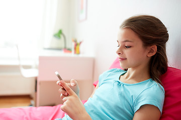 Image showing smiling girl texting on smartphone at home