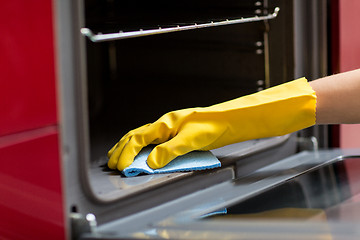 Image showing hand with rag cleaning oven at home kitchen