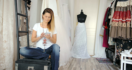 Image showing Woman in tailor\'s shop with phone