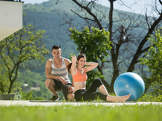 Image showing woman with personal trainer doing morning yoga exercises