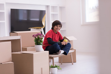 Image showing boy sitting on the table with cardboard boxes around him