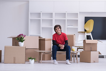 Image showing boy sitting on the table with cardboard boxes around him