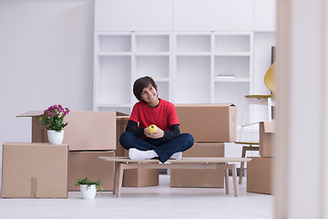 Image showing boy sitting on the table with cardboard boxes around him