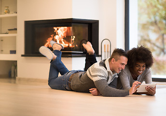 Image showing multiethnic couple using tablet computer on the floor