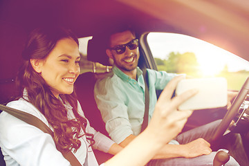 Image showing happy couple in car taking selfie with smartphone