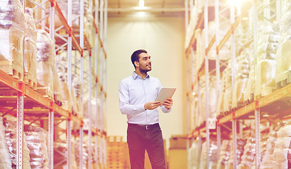 Image showing happy businessman with tablet pc at warehouse