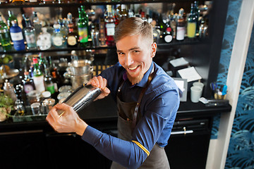 Image showing happy barman with shaker preparing cocktail at bar