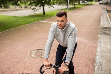 Image showing young man riding bicycle on city street