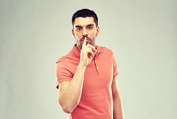 Image showing young man making hush sign over gray background