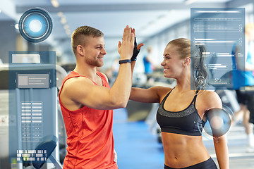 Image showing smiling man and woman doing high five in gym