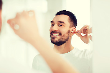 Image showing man cleaning ear with cotton swab at bathroom