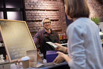 Image showing happy barman and woman paying money at cafe