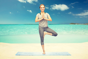 Image showing woman making yoga in tree pose on beach 