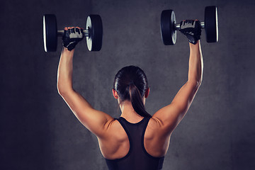 Image showing young woman flexing muscles with dumbbells in gym