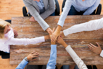 Image showing business people holding hands at office table