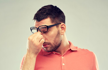 Image showing tired man with eyeglasses touching nose bridge