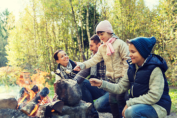 Image showing happy family roasting marshmallow over campfire