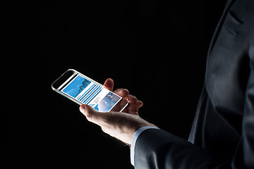 Image showing close up of businessman with charts on smartphone