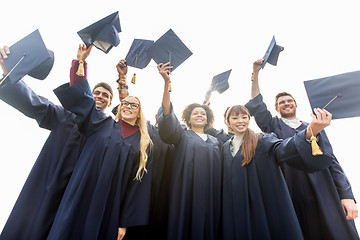 Image showing happy students or bachelors waving mortar boards