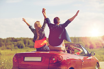 Image showing happy friends driving in cabriolet car at country