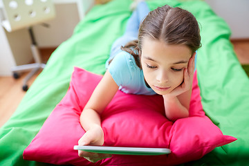 Image showing smiling girl with tablet pc lying in bed at home