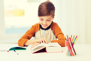 Image showing smiling, student boy reading book at home