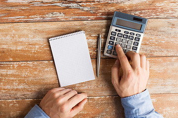 Image showing close up of hands with calculator and notebook