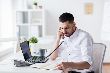 Image showing businessman with pad calling on phone at office