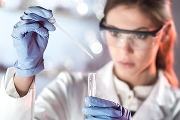 Image showing Young scientist pipetting in life science laboratory.