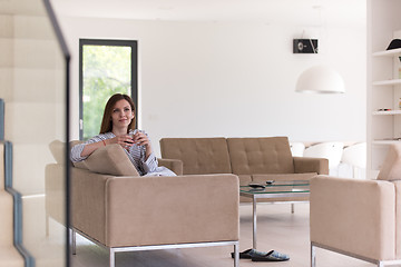 Image showing young woman in a bathrobe enjoying morning coffee