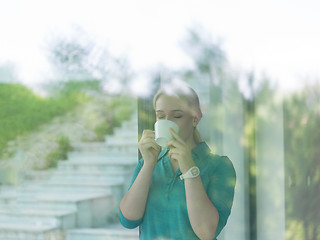 Image showing young woman drinking morning coffee by the window